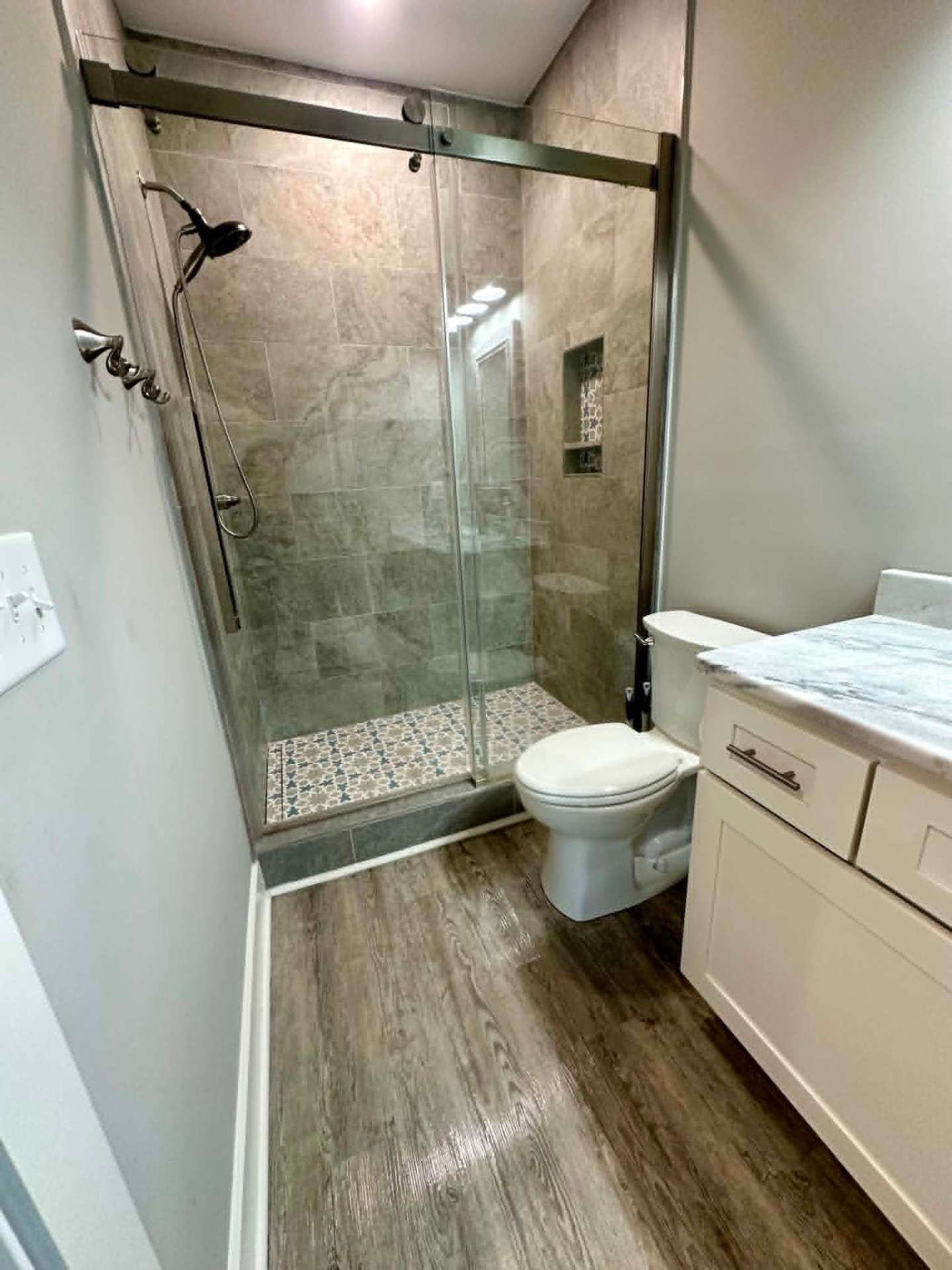 Tiled walk-in shower with glass doors, sparkling clean